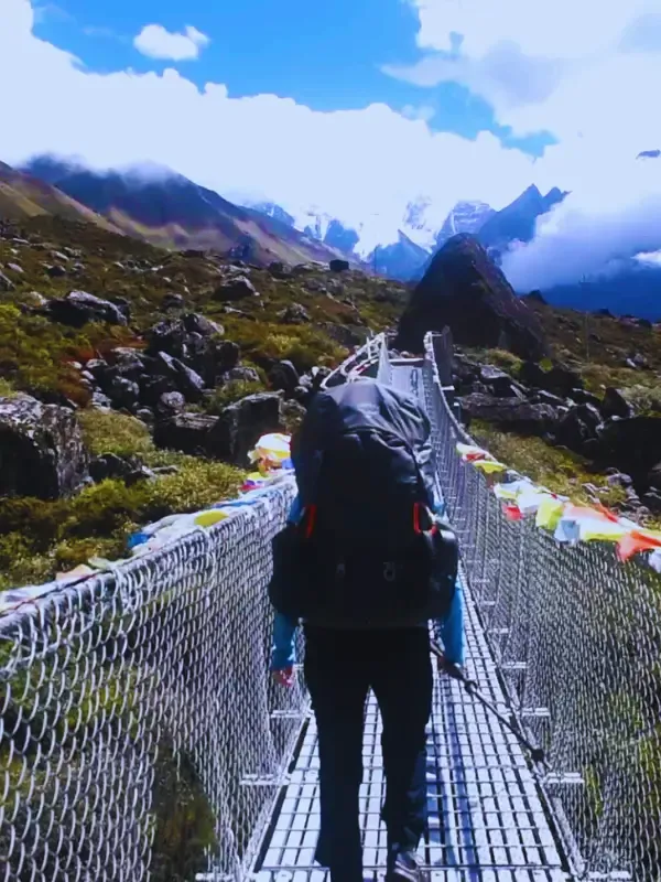 Trekker-crossing-a-suspension-bridge-with-mountain-views-on-a-Nepal-trekking-trail